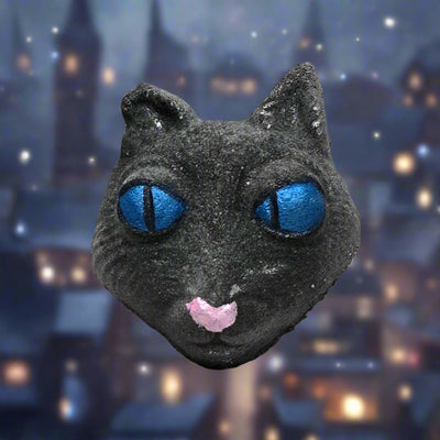 Topher’s Beard and Soap Co. The Cat Bath Bomb – hand-painted Coraline-inspired bath bomb styled against a twilight backdrop of a historic town with glowing orbs of light, capturing the mysterious and magical essence of the character.