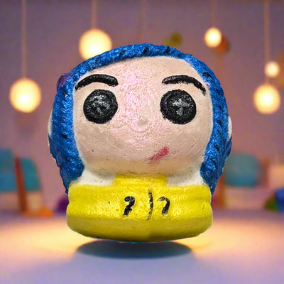 Topher’s Beard and Soap Co. Other Caroline Bath Bomb – hand-painted Coraline-inspired bath bomb displayed on a pastel background with soft hanging lights, styled to reflect the eerie charm and whimsical tone of the Other World.