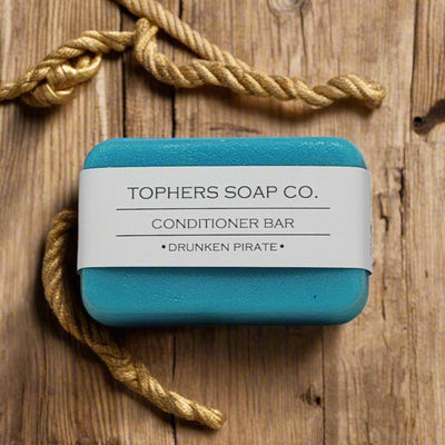 Topher's Soap Co. Drunken Pirate Conditioner Bar – vibrant turquoise bar with minimalist label, styled with nautical rope on rustic wood for a rugged, maritime look