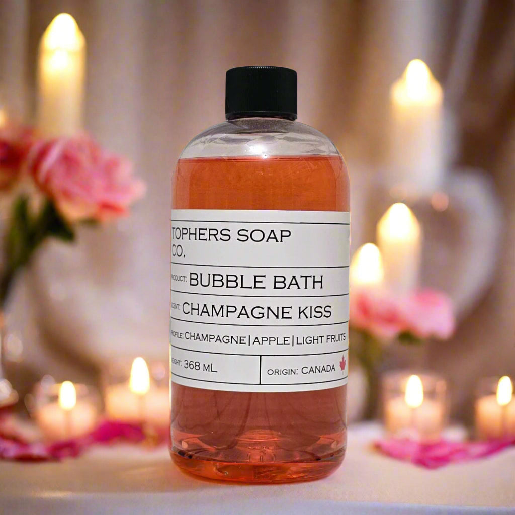 Topher's Beard and Soap Co. Champagne Kiss Bubble Bath – 368 ml bottle of pink bubble bath with champagne, apple, and fruit notes, styled with roses, petals, and candlelight for a romantic spa setting