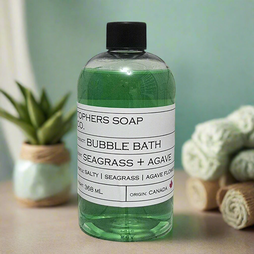 Topher's Beard and Soap Co. Seagrass + Agave Bubble Bath – 368 ml bottle of green bubble bath with a minimalist label, displayed on a spa-inspired background with rolled towels and a potted succulent