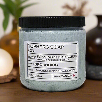 Topher's Beard and Soap Co. Grounding Foaming Sugar Scrub – 226 g jar of earthy green whipped scrub with patchouli, spice, and fall leaf scent notes, displayed on a wooden surface with warm-toned decor