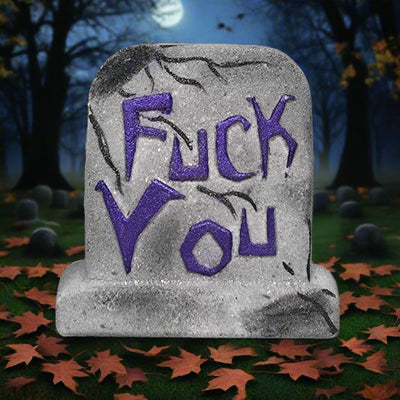 Topher’s Beard and Soap Co. FUCK YOU Tombstone Bath Bomb – hand-painted grey bath bomb shaped like a tombstone with bold purple lettering, set against a spooky graveyard backdrop with a full moon, autumn leaves, and eerie nighttime trees.

