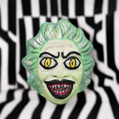 Topher’s Beard and Soap Co. Beetlejuice Bath Bomb – hand-painted bath bomb featuring a green-haired, sharp-toothed character design inspired by Beetlejuice, set against a black and white striped background to reflect the film’s iconic visual style.

