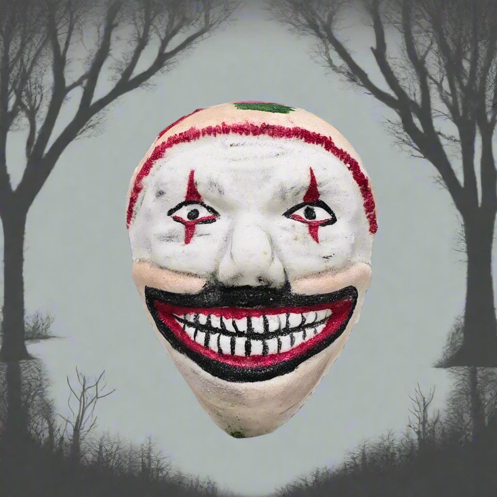 Topher’s Beard and Soap Co. Twisty the Clown Bath Bomb – hand-painted bath bomb inspired by Twisty from American Horror Story, styled with a silhouette of leafless trees and grey skies in the background to reflect the eerie, unsettling tone of the character.