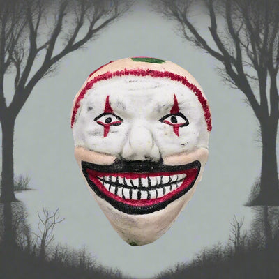 Topher’s Beard and Soap Co. Twisty the Clown Bath Bomb – hand-painted bath bomb inspired by Twisty from American Horror Story, styled with a silhouette of leafless trees and grey skies in the background to reflect the eerie, unsettling tone of the character.