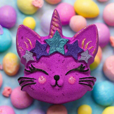 Hand-painted, bright purple bath bomb from Tophers Soap Co. in Brantford, Ontario, shaped like a cat's face with a unicorn horn, glittery stars, and whiskers, surrounded by pastel bath bombs, showcasing a magical and locally handcrafted bath product with a sweet Pink Sugar scent.