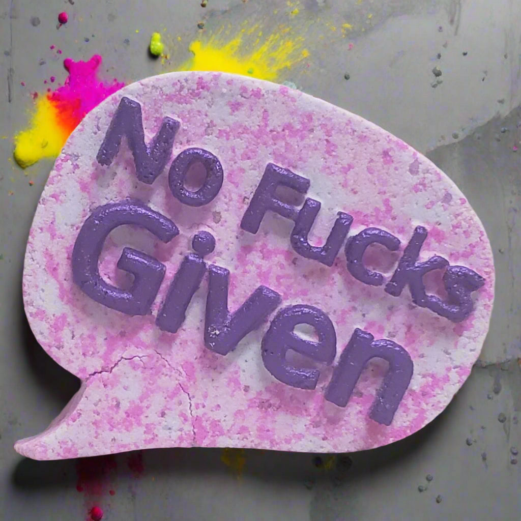 Hand-painted, speech bubble-shaped bath bomb from Tophers Soap Co. in Brantford, Ontario, with the text "No Fucks Given" in purple, surrounded by vibrant color splashes.