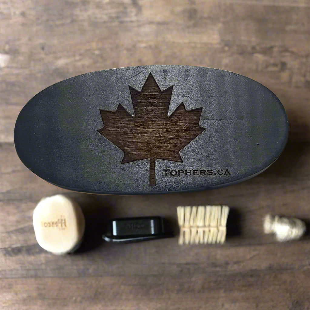 Oval wooden beard brush from Tophers Beard Co. in Brantford, Ontario, featuring a prominent laser-cut Canadian maple leaf and the website "TOPHERS.CA," shown with its boar and synthetic bristles, emphasizing its natural quality.