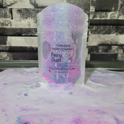 Resealable pouch of Tophers Soap Co. Fairy Dust foaming bath bomb powder in Unicorn scent, overflowing with colorful pink, purple, and white foam and bubbles, demonstrating its magical fizzing action and highlighting its origin in Brantford, Ontario, Canada.