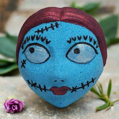 A unique, hand-painted bath bomb in the likeness of Sally Skellington, showcasing the intricate stitched details and promising a sweet and effervescent bath experience. Handcrafted in Brantford, Canada.