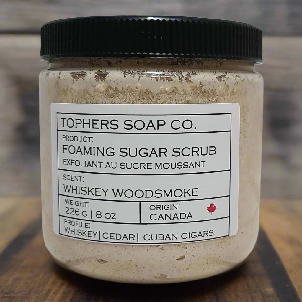 Creamy brown  sugar scrub in a clear jar with a black lid against a white brick background