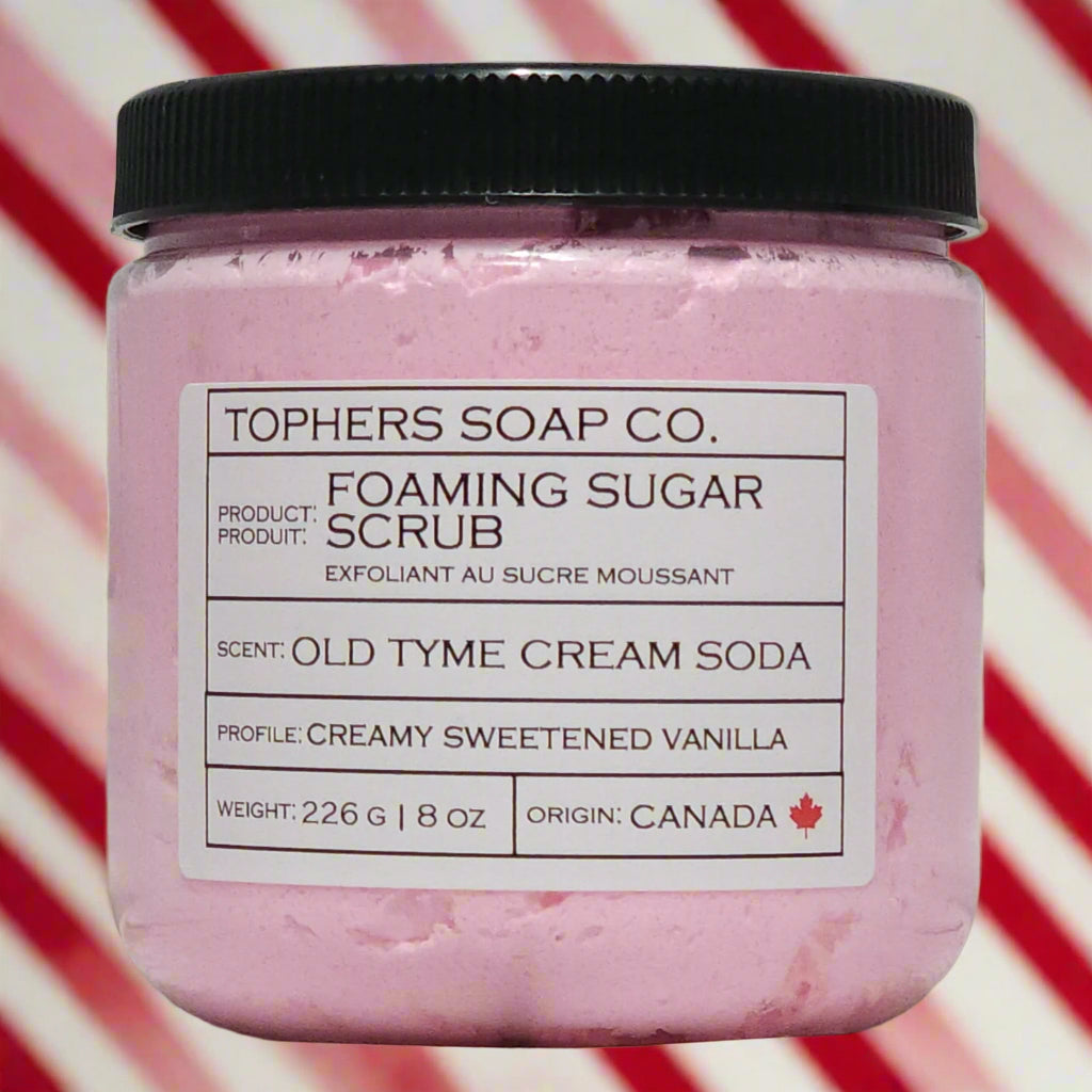 Cotton Candy Pink sugar scrub in a clear jar with a black lid against a white brick background