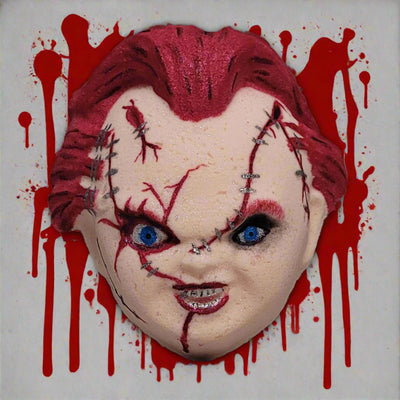 Topher's Beard and Soap Co. Chucky hand-painted bath bomb featuring a detailed horror doll face with blood-splattered background, bright blue eyes, and stitched scars, perfect for Halloween or horror lovers.