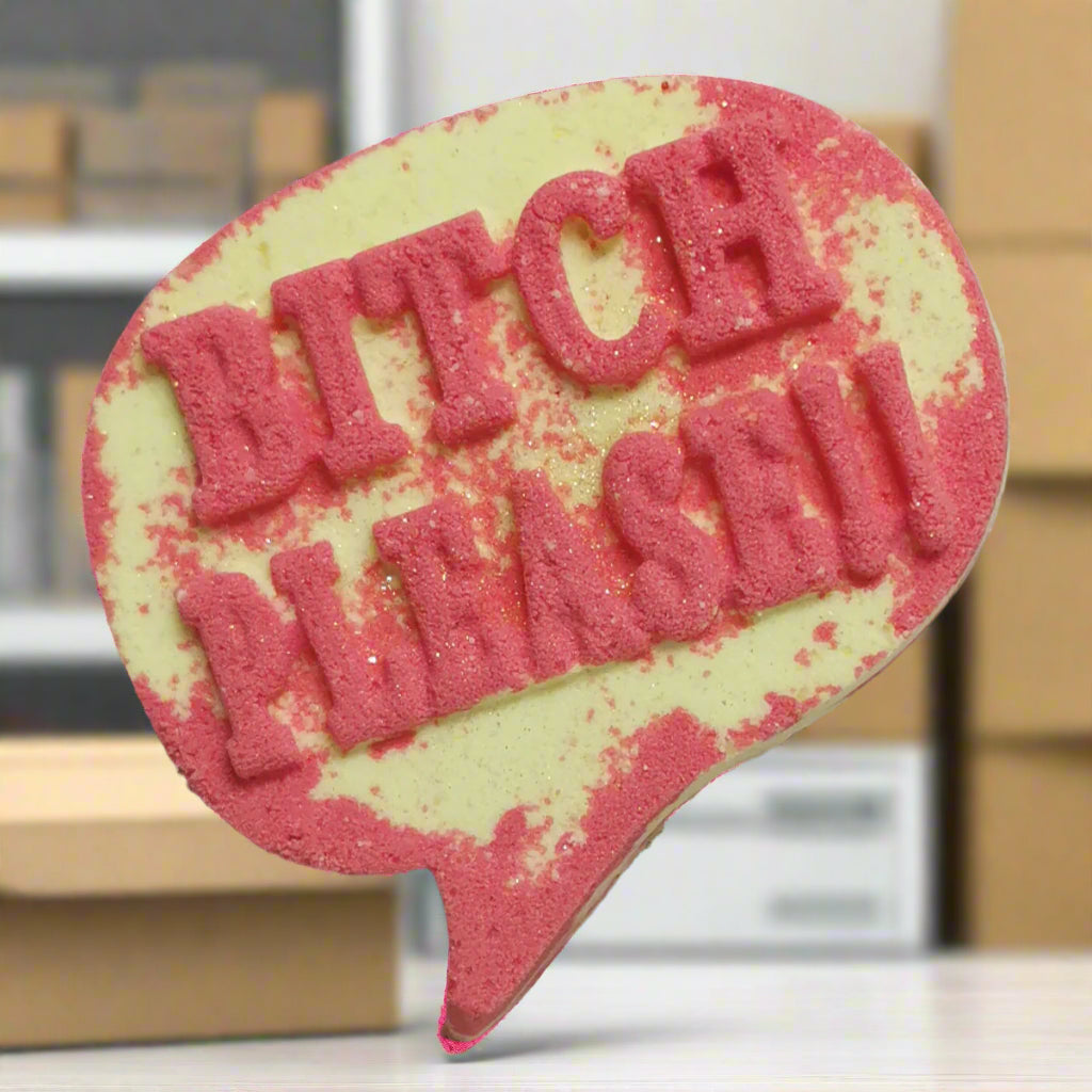 A speech bubble-shaped bath bomb with a light yellow base and the words "BITCH PLEASE" in raised pink lettering with glitter, handcrafted by Tophers Soap Co. in Brantford, Ontario.
