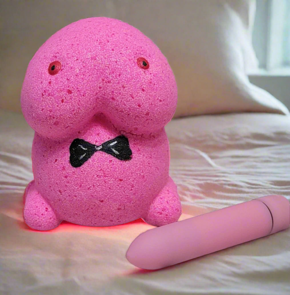 Mr. Chubby bath bomb glowing on a bed with his secret companion revealed. Handmade for a fun and frisky bath time by Tophers Soap Co. in Brantford.