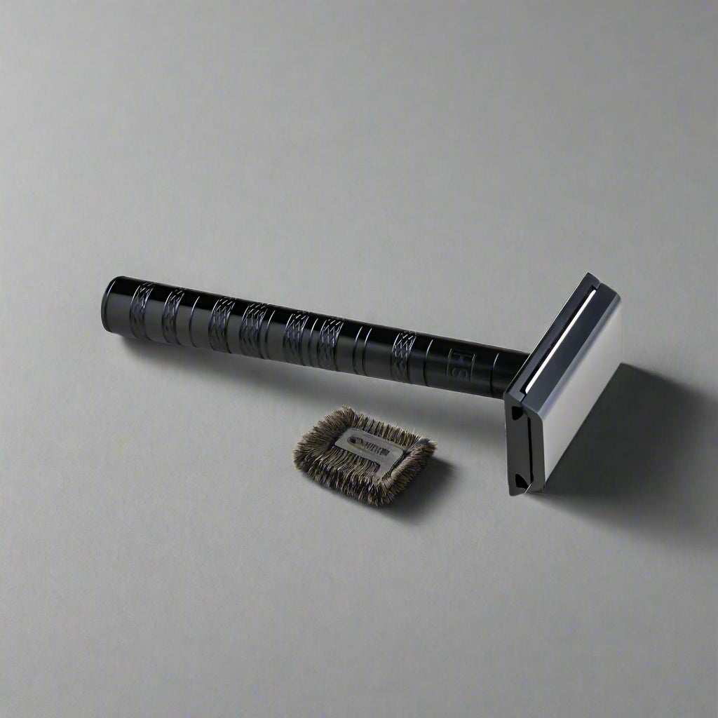 Black Henson AL13 Safety Razor lying on a gray surface with its small cleaning brush - Tophers Beard and Soap Co.